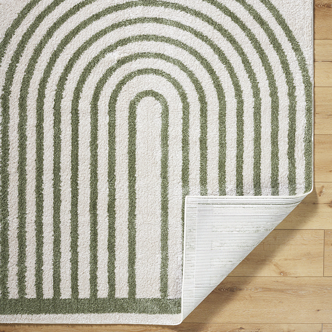 close up image of green and cream rug with corner folded over to show material underneath