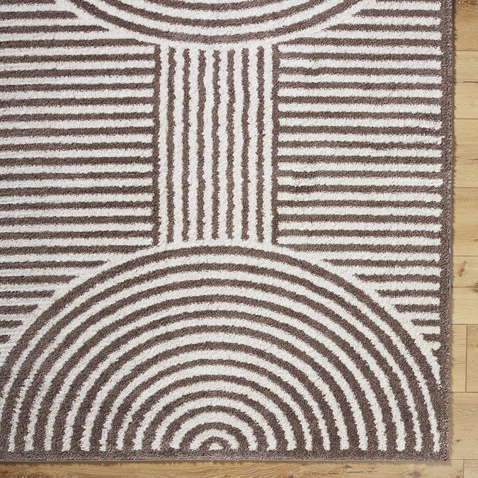 close up image of corner of cream and brown abstract rug