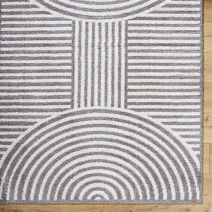 close up image of corner of dark grey lined arch geometric rug