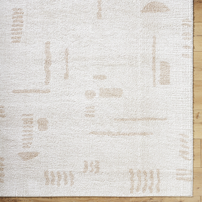 close up image of corner of cream rug with beige abstract line pattern