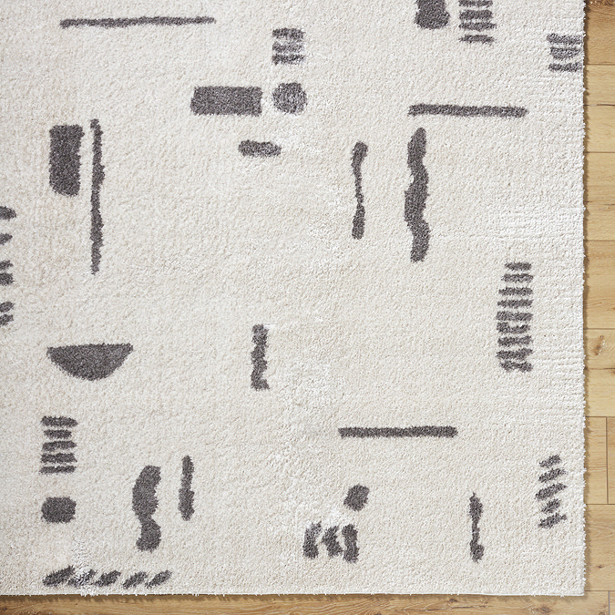 close up image of soft cream rug with dark grey abstract line pattern