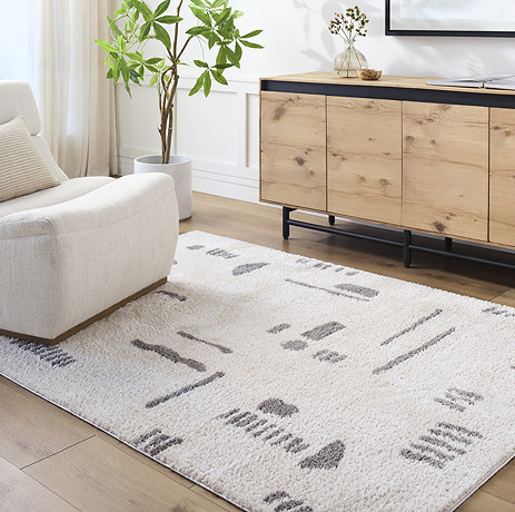 image of soft cream rug with dark grey abstract line and shape pattern, on light wood flooring of living room