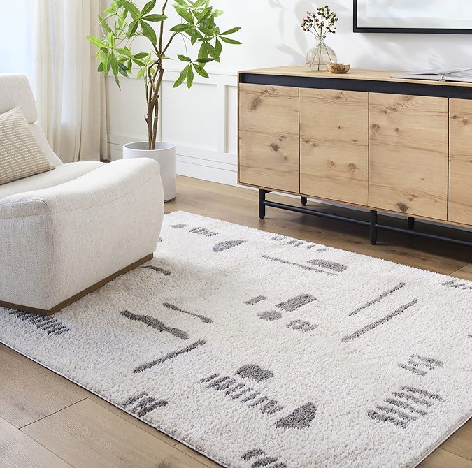 image of soft cream rug with dark grey abstract line and shape pattern, on light wood flooring of living room
