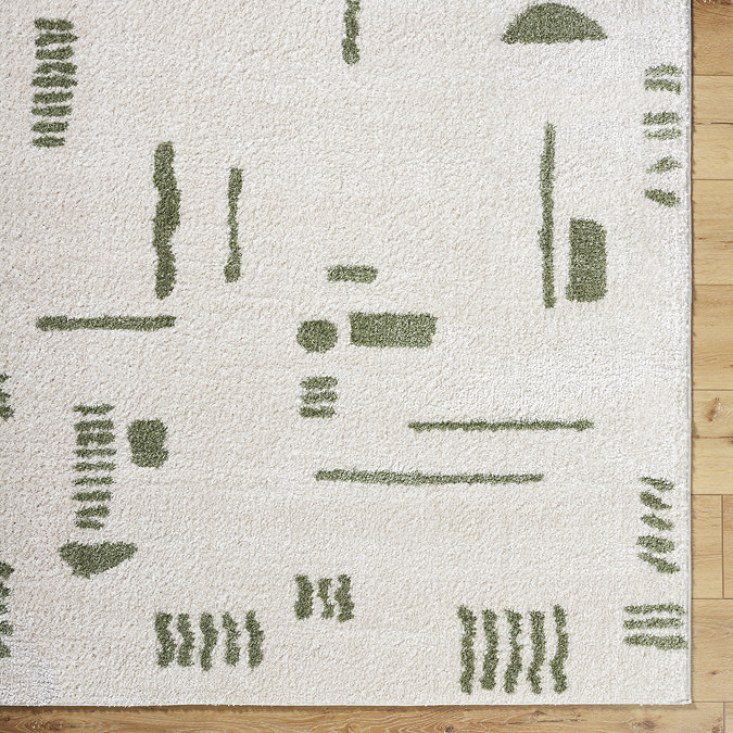close up image of corner of cream rug with green abstract lines