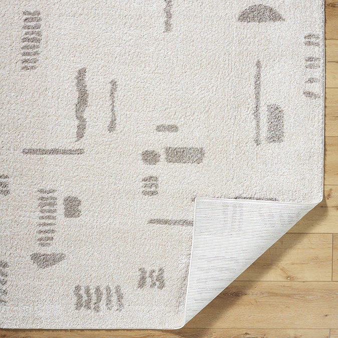 image of soft cream rug with light grey abstract line patterns, corner folded up slightly to reveal material underneath