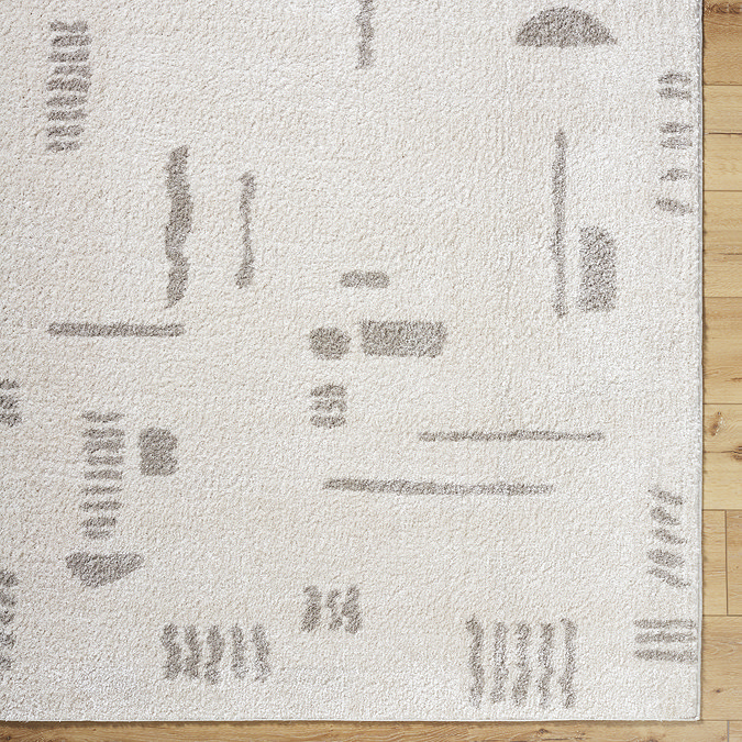 close up image of corner of soft cream rug with light grey line and shape patterns