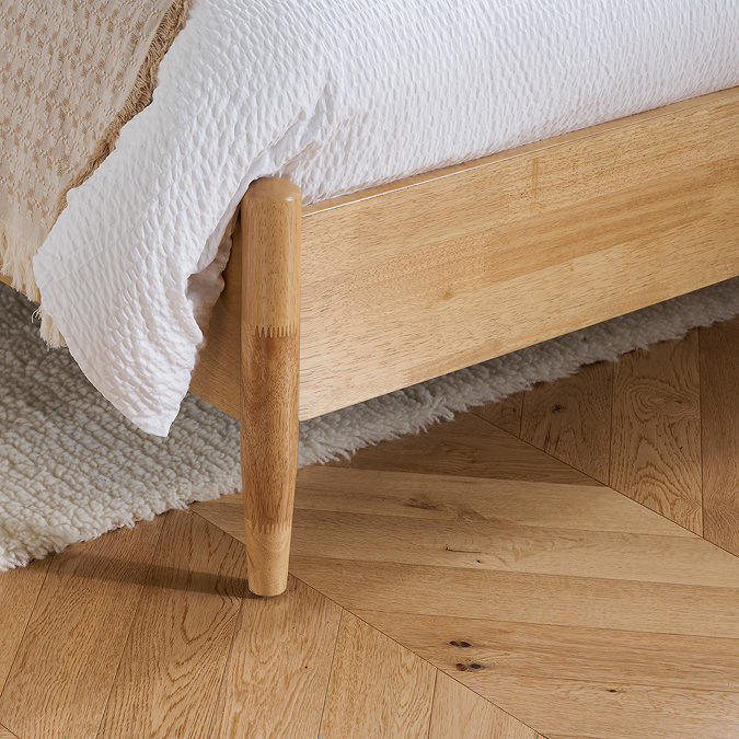 close up image on spindled feet and oak footboard of bed