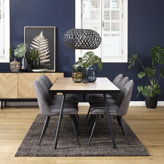 image of light oak herringbone and black metal dining table surrounded by grey chairs and with matching sideboard in the background