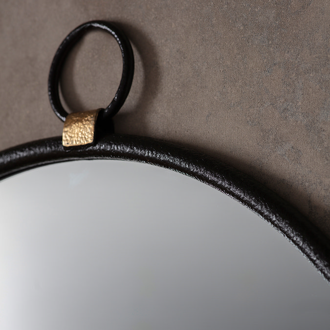 close up on round black mirror with round handle hung on hook