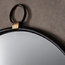 close up on round black mirror with round handle hung on hook