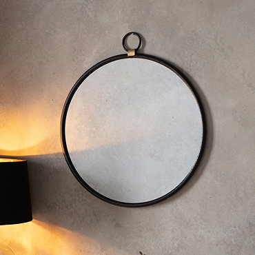 close up on round black mirror with round handle hung on hook