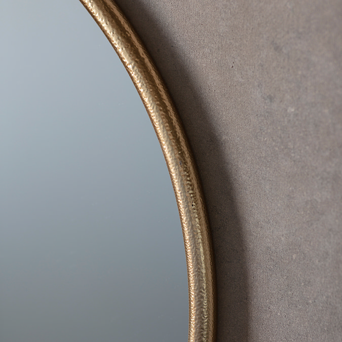 close up image of gold edge of round metal wall mounted mirror