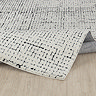 image of ivory and black rug with distressed design, ruched up slightly to show its high pile