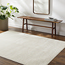 image of ivory cream rug with distressed pattern on dark wood flooring next to walnut bench and potted plant