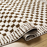close up image of ivory and brown checkered rug with lined border, ruched up slightly to show thickness