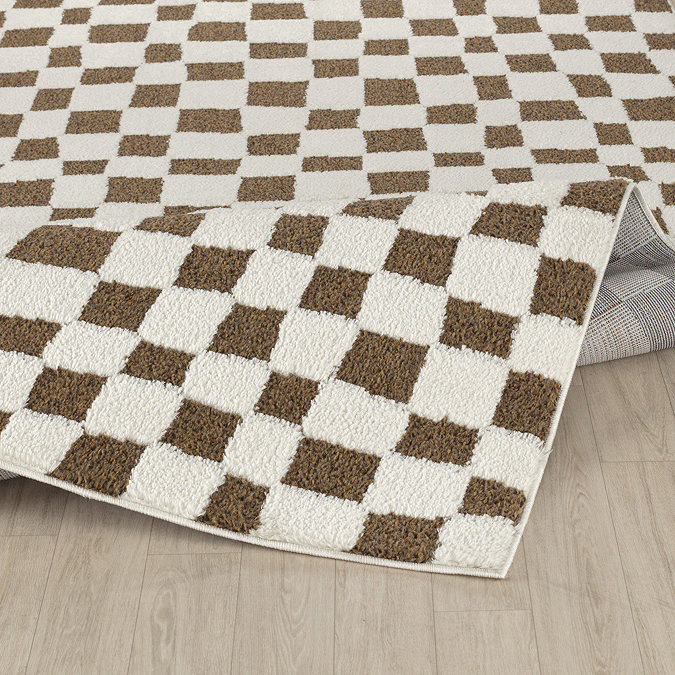 image of brown and ivory checkered soft rug on light wood flooring, slightly folded up