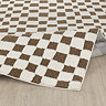 image of brown and ivory checkered soft rug on light wood flooring, slightly folded up