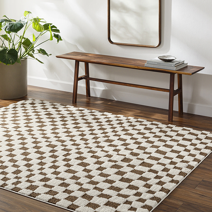 image of brown and ivory checkered rug on dark wood flooring next to walnut bench and potted plant