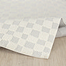 image of soft ivory checkered rug folded slightly on light wood flooring