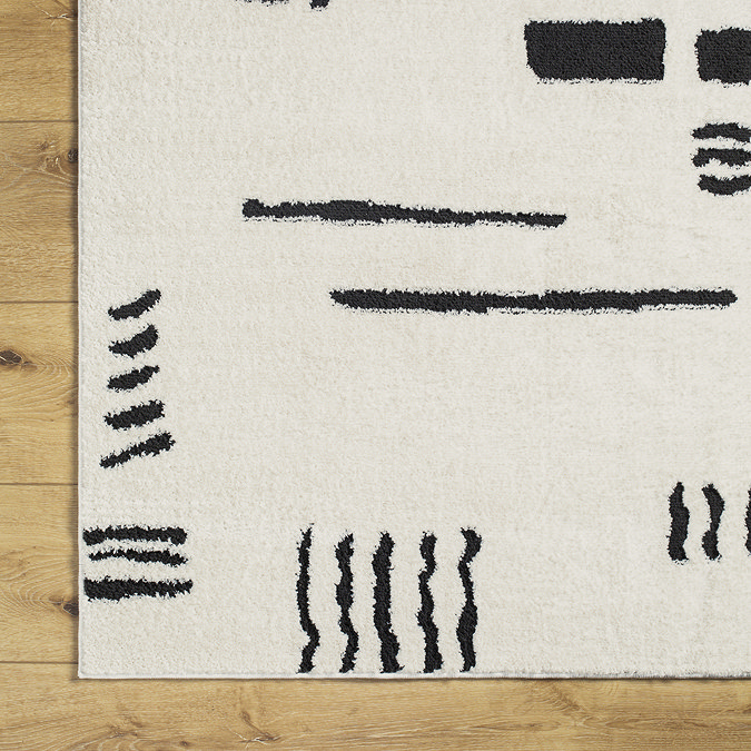 close up image of corner of ivory rug with black abstract shapes