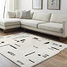 image of soft ivory rug with black abstract geometric pattern impressed in the fabric, on light wood flooring of living room