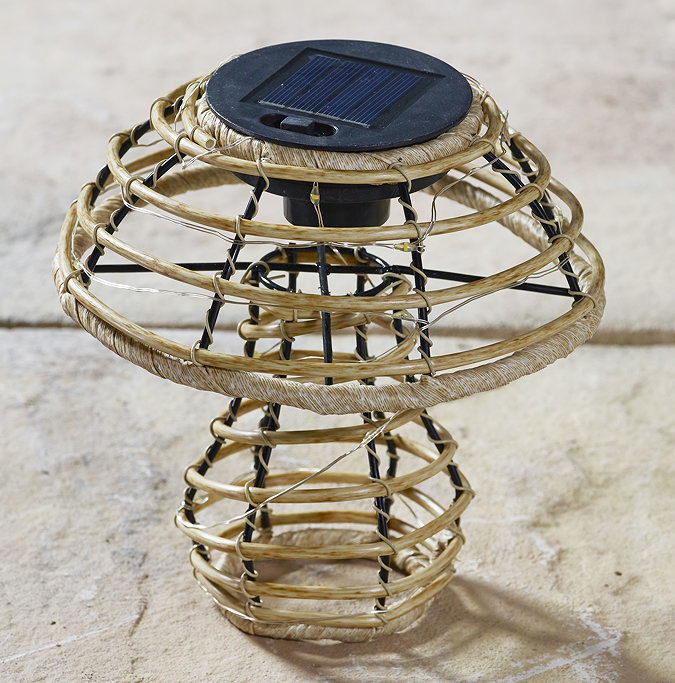 close up image of rattan mushroom with solar cap and lights wrapped inside it, taken at daytime, switched off on patio