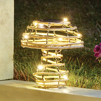 image of small rattan mushroom with small lights wrapped inside it, emitting warm glow on garden patio at dusk