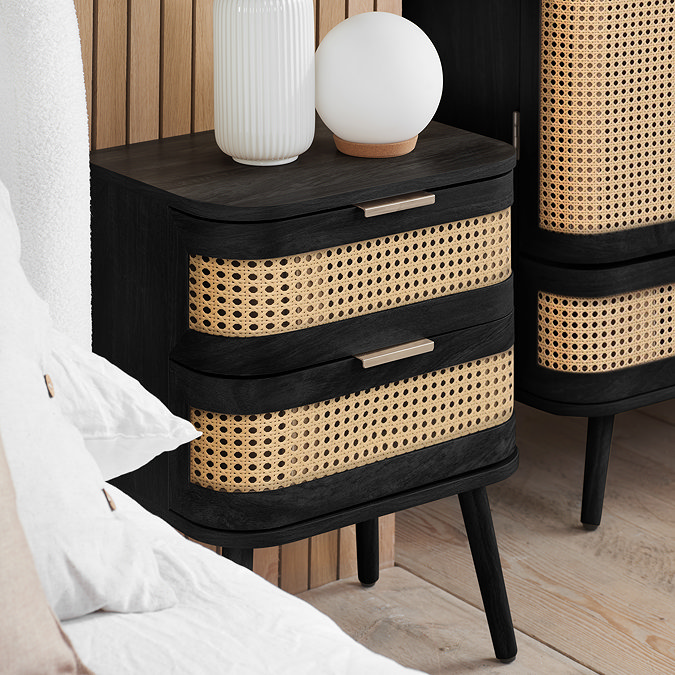 side on angled image of black and rattan bedside table
