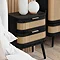 side on angled image of black and rattan bedside table