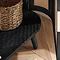 close up image of curved edge of rattan tv unit, door slightly open to reveal wicker basket inside, and light reflecting through rattan door on to black shelf