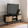 image of black wooden tv stand with two rattan doors on either side of a central shelving space, pushed up against light grey wall with tv and faux plant on top