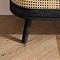 close up image of black wooden legs of black and rattan sideboard