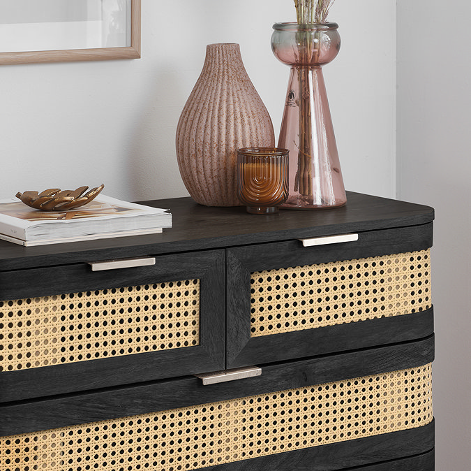close up image of front of black 5 drawer chest with decorative accessories on top