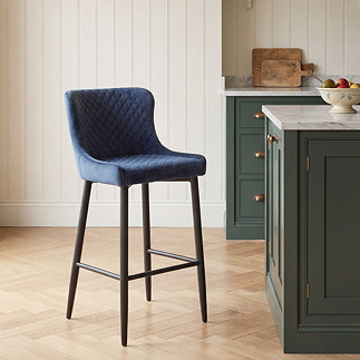 image of single blue velvet bar stool on herringbone light wood floor next to country kitchen counter