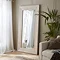 large whitewashed mirror, stood against a pale green living room wall