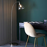 image of gently arched nickel floor lamp with clear glass shade and warm bulb standing over a navy desk