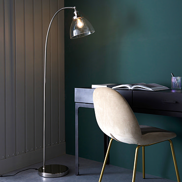 close up image of top of gently arched floor lamp in bright nickel, with clear glass shade ensconcing a warm white LED bulb