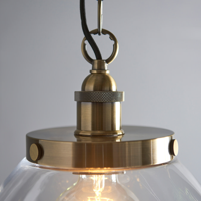close up image on antique brass fixture of large clear glass pendant light