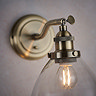 close up image on top of antique brass wall light with clear glass shade, through which can be seen a warm white filament LED bulb