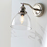zoomed out photo of wall light on marble-effect kitchen wall with glass shade and nickel fixture