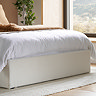 close up on bottom of ottoman bed with white base, resting on white woven rug on wooden floor