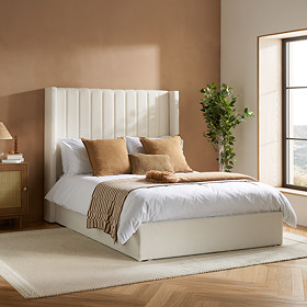 image of ottoman bed with white boucle headboard against a light terracotta wall with orange accent cushions