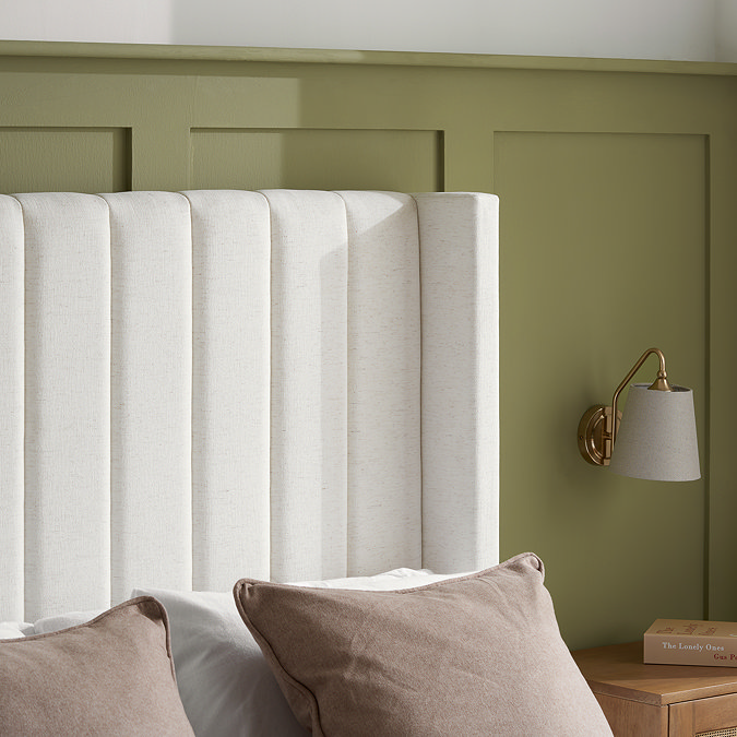 closer image of cream linen headboard against sage green wall, highlighting smooth fabric