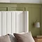 closer image of cream linen headboard against sage green wall, highlighting smooth fabric