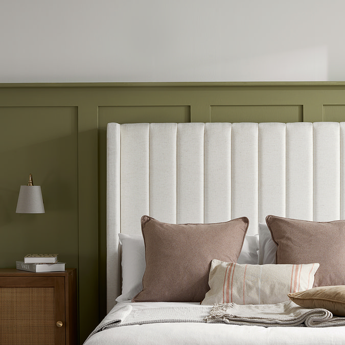 close up on cream fabric headboard of ottoman bed, with mauve cushions resting against it
