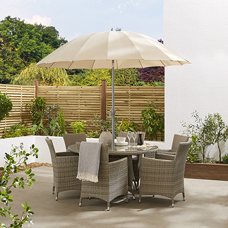 image of ecru parasol in light brown table with rattan chairs, on sunny patio