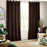 image of dark brown curtains open over a living room window with armchair next to it with brown and green cushions