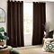 image of dark brown curtains open over a living room window with armchair next to it with brown and green cushions