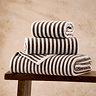image of stack of chocolate brown towels on wooden bench