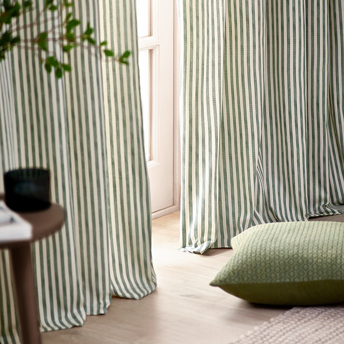 close up on bottom of green striped curtains, lightly brushing wooden floor